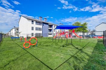 A playground with a slide and swings in front of a building.